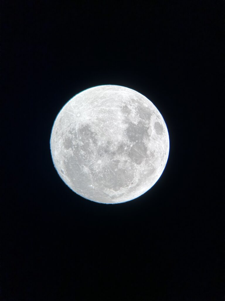 Close-up of a bright full Moon against a dark night sky, revealing craters and maria.